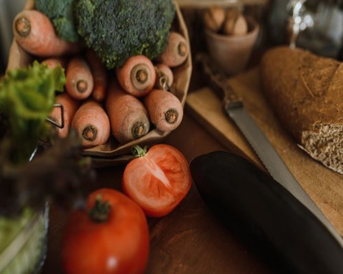 fresh vegetables and bread on a rustic kitchen table